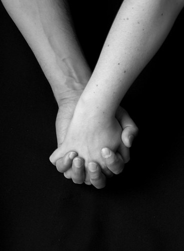 Two hands clasped together in a supportive gesture, symbolizing comfort and support